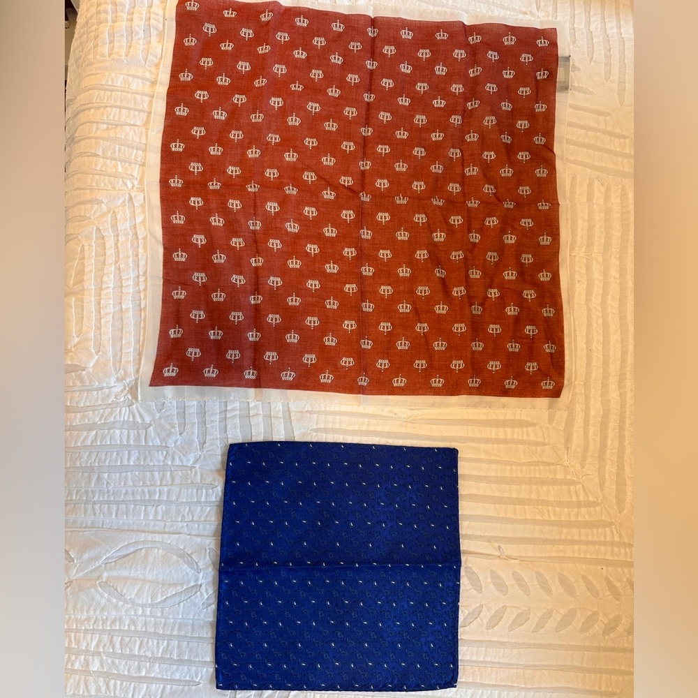 Set of two pocket squares. 1 red with crowns design, 1 blue paisley.